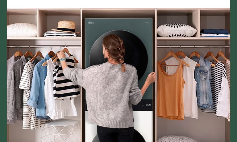 A WashTower is installed between the hangers, and a woman is choosing clothes in front.